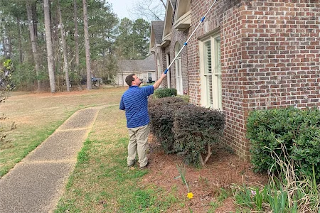 technician sweeping exterior of home for pests